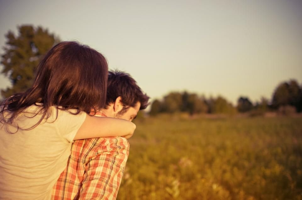 Pareja abrazada en un campo al atardecer